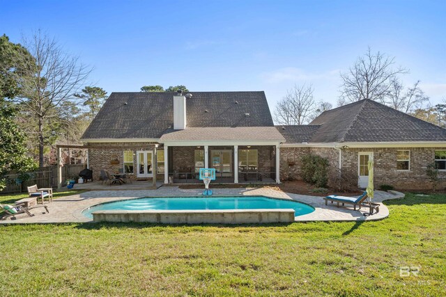 back of property featuring brick siding, fence, a lawn, french doors, and a patio