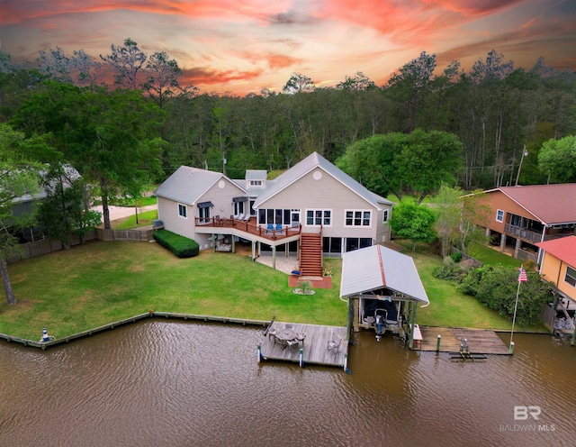 exterior space with fence, boat lift, a deck with water view, stairs, and a forest view