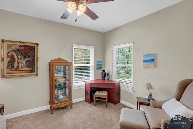 living area with a ceiling fan, baseboards, and light carpet