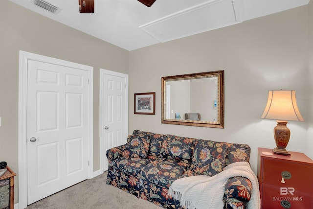 living area featuring carpet floors, ceiling fan, attic access, and visible vents