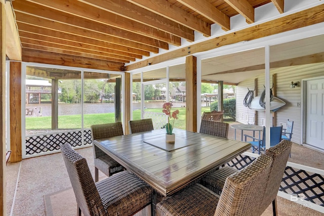 sunroom featuring plenty of natural light, outdoor dining area, and a water view