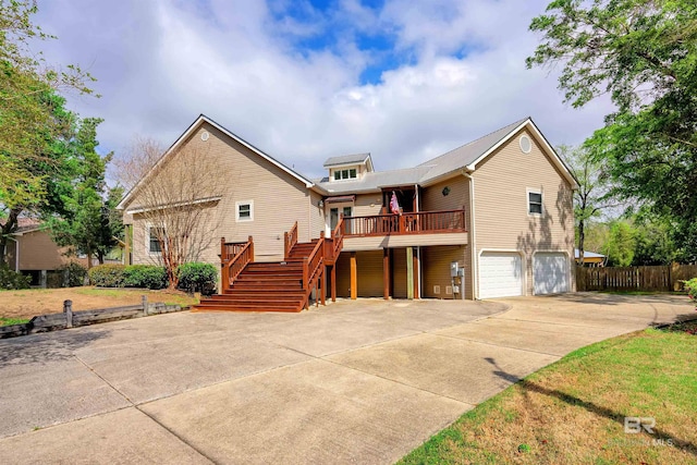 view of front facade featuring fence, stairs, a garage, a wooden deck, and driveway