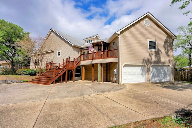 rear view of house featuring concrete driveway, an attached garage, and stairway