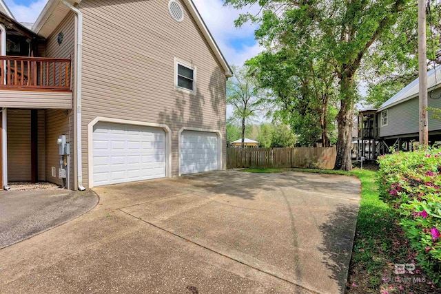 view of side of home featuring a garage, fence, and driveway