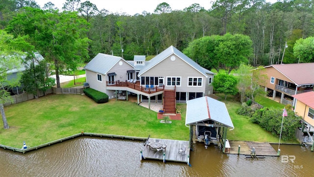 back of house with stairway, fence, a deck with water view, boat lift, and a wooded view