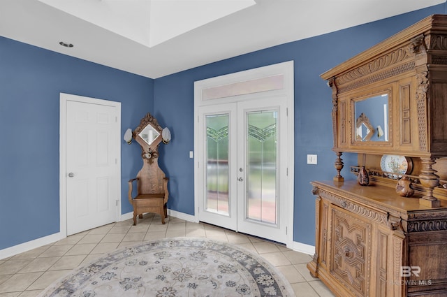 sitting room with a skylight, baseboards, french doors, and light tile patterned flooring