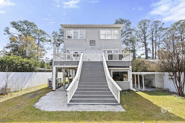 back of house with a deck, a patio area, and a lawn