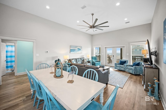 dining room with french doors, ceiling fan, light hardwood / wood-style flooring, and a high ceiling