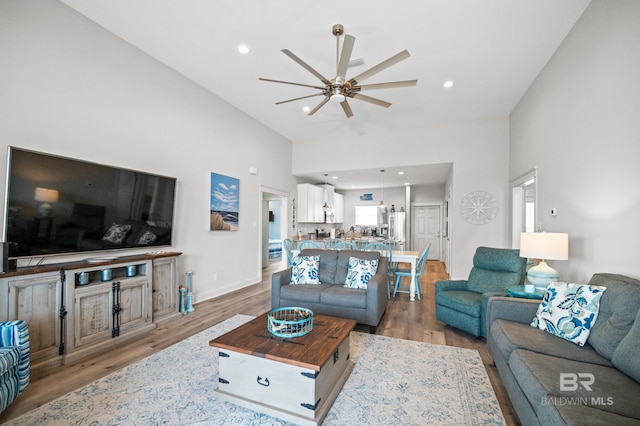 living room featuring light hardwood / wood-style flooring, high vaulted ceiling, and ceiling fan