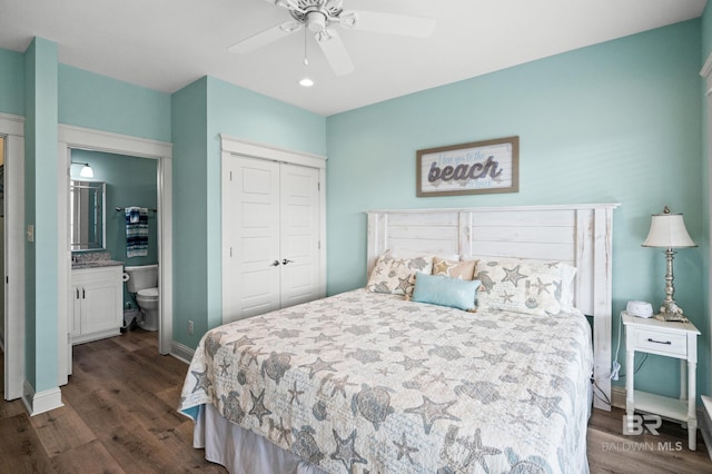 bedroom featuring ensuite bath, dark wood-type flooring, a closet, and ceiling fan