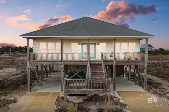 back house at dusk featuring a carport and a porch