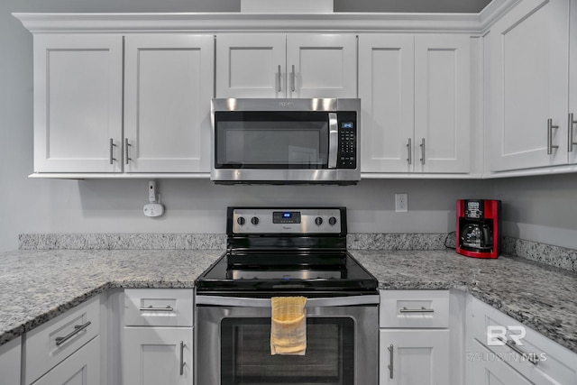 kitchen featuring stainless steel appliances, light stone countertops, and white cabinets