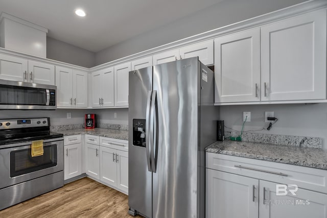 kitchen featuring stainless steel appliances, light stone countertops, light wood-type flooring, and white cabinets