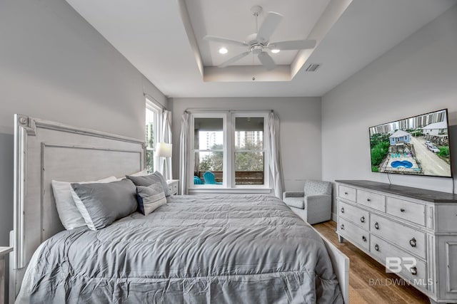 bedroom featuring hardwood / wood-style floors, a tray ceiling, and ceiling fan