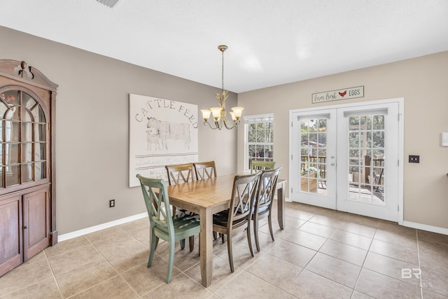 tiled dining space featuring a chandelier and french doors