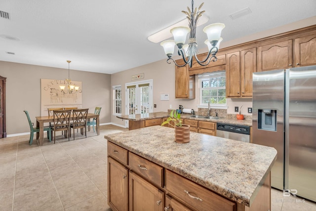 kitchen with a kitchen island, appliances with stainless steel finishes, and an inviting chandelier