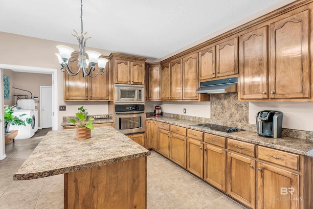 kitchen featuring a center island, an inviting chandelier, decorative light fixtures, stainless steel appliances, and washing machine and clothes dryer