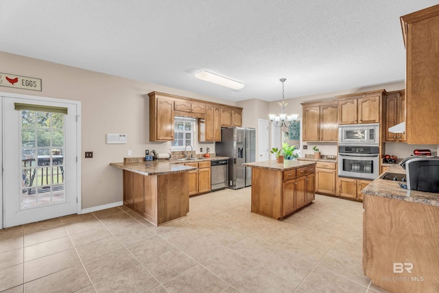 kitchen featuring sink, hanging light fixtures, stainless steel appliances, a notable chandelier, and a kitchen island