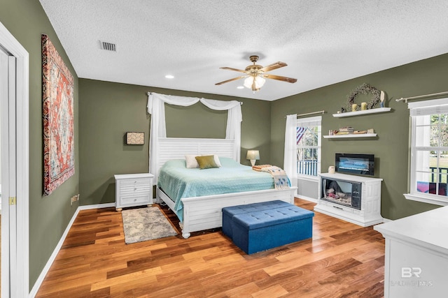 bedroom featuring a textured ceiling, light hardwood / wood-style flooring, and ceiling fan