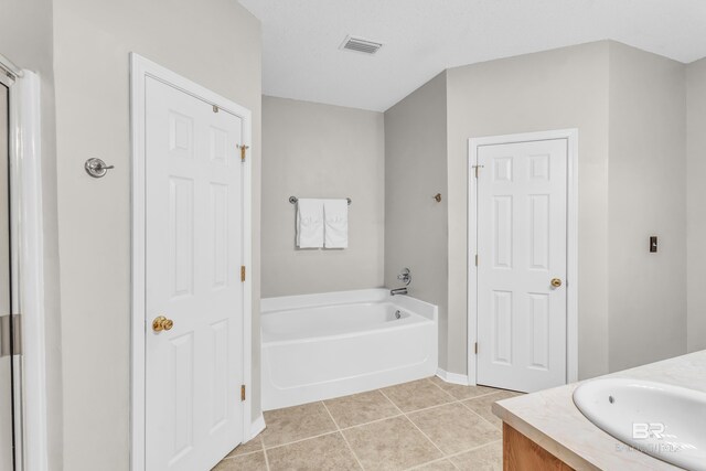 bathroom with tile patterned flooring, vanity, and a tub to relax in