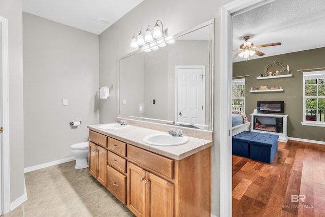 bathroom featuring a textured ceiling, vanity, ceiling fan, hardwood / wood-style flooring, and toilet