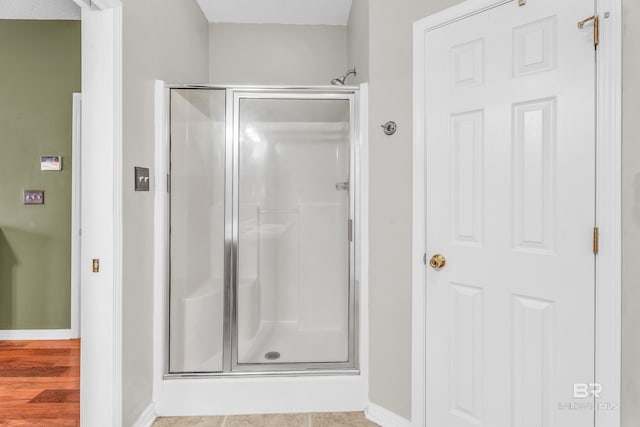 bathroom with hardwood / wood-style floors, a shower with door, and a textured ceiling