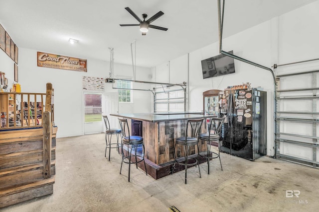 interior space featuring a kitchen breakfast bar, ceiling fan, a kitchen island, and black refrigerator with ice dispenser