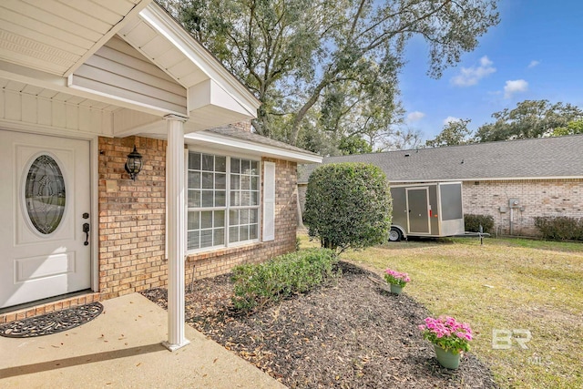 entrance to property featuring a yard and brick siding