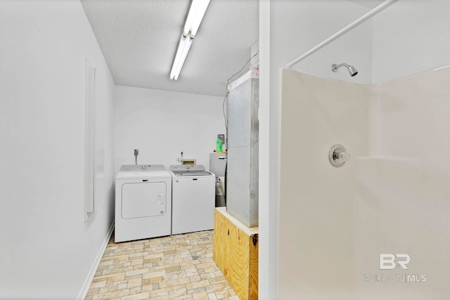 clothes washing area with laundry area, independent washer and dryer, a textured ceiling, and baseboards