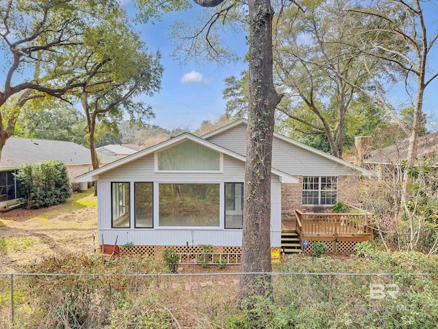 rear view of house featuring a sunroom and a wooden deck