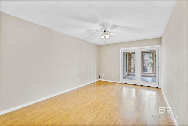 unfurnished room featuring a textured ceiling, baseboards, wood finished floors, and french doors