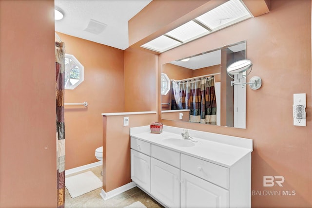 bathroom with baseboards, plenty of natural light, vanity, and toilet