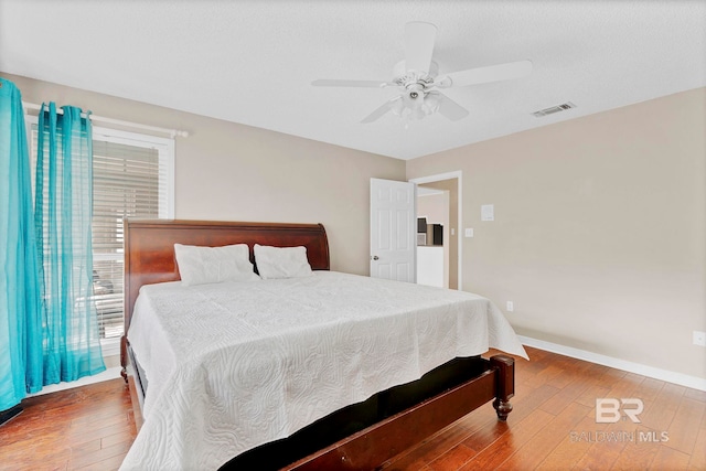 bedroom with wood-type flooring, visible vents, ceiling fan, and baseboards