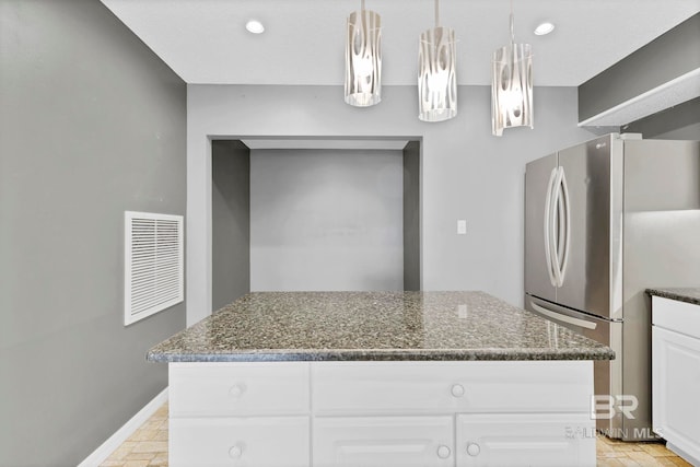 kitchen with visible vents, baseboards, white cabinets, freestanding refrigerator, and dark stone countertops