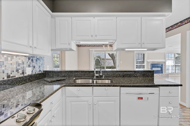 kitchen with stove, white dishwasher, a sink, and white cabinets