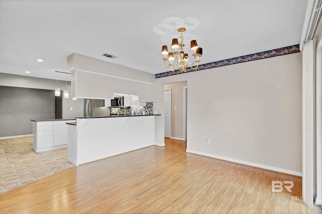 kitchen featuring dark countertops, an inviting chandelier, and light wood-style flooring