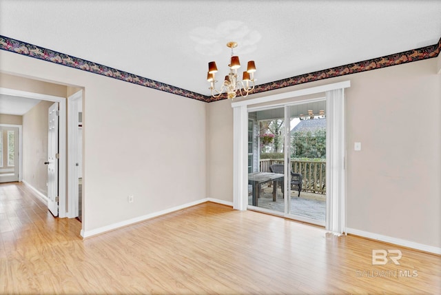 empty room featuring baseboards, a textured ceiling, wood finished floors, and an inviting chandelier