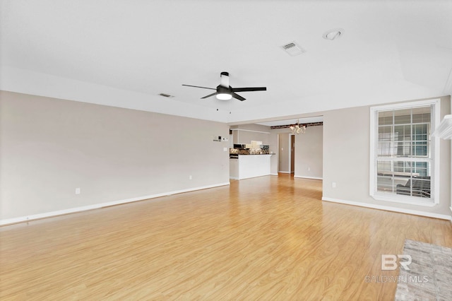 unfurnished living room featuring light wood-type flooring, visible vents, baseboards, and ceiling fan with notable chandelier