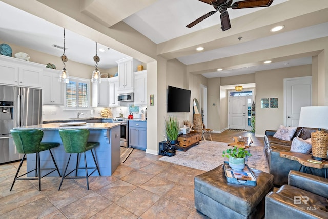 kitchen with white cabinetry, stainless steel appliances, hanging light fixtures, and a kitchen island