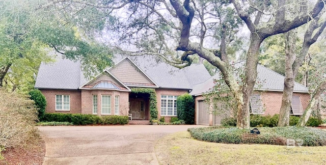 view of front of house with a garage, a standing seam roof, brick siding, and driveway