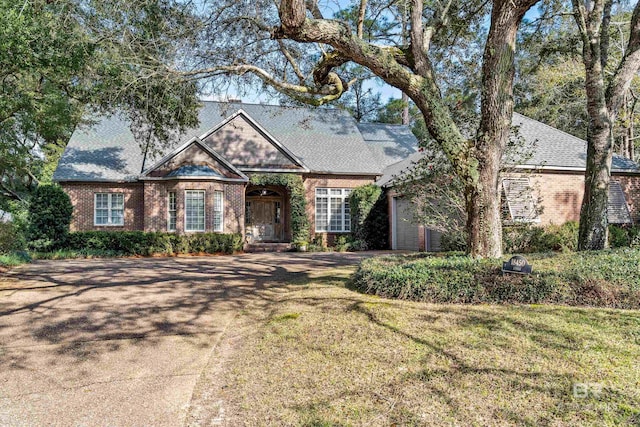 view of front of house featuring a garage, brick siding, a front lawn, and a shingled roof