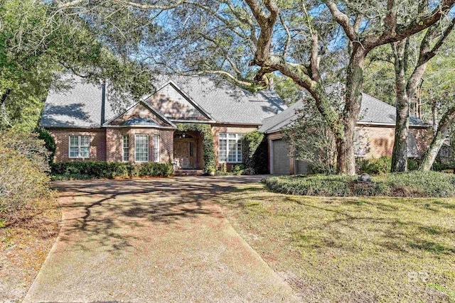 view of front of house featuring a front yard, brick siding, driveway, and an attached garage