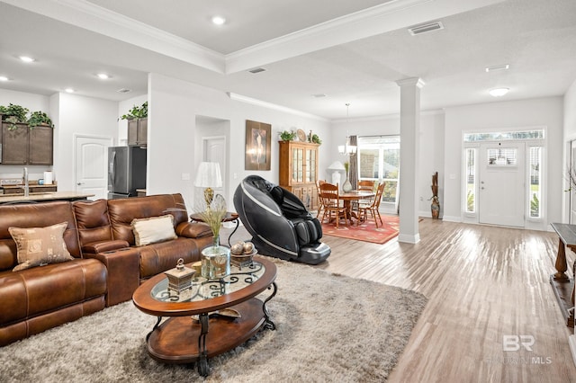 living area with light wood-type flooring, visible vents, recessed lighting, crown molding, and decorative columns