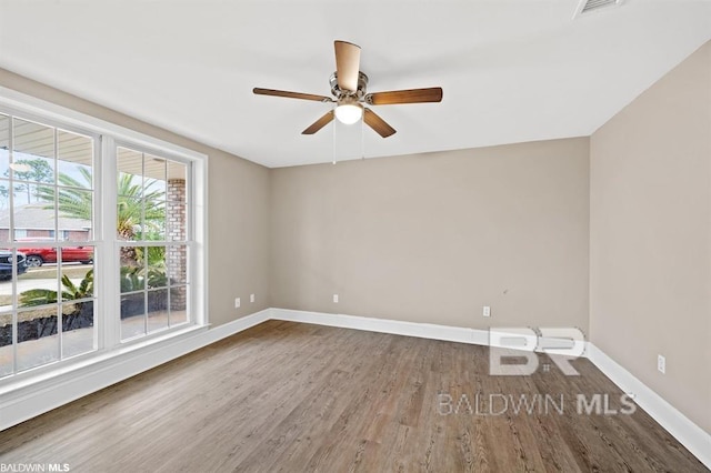 spare room featuring visible vents, wood finished floors, a ceiling fan, and baseboards