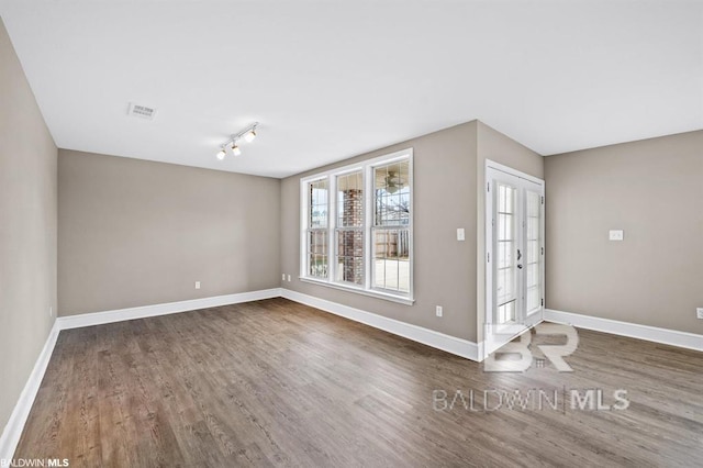 spare room featuring visible vents, baseboards, and wood finished floors