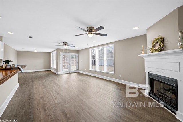 living area featuring baseboards, a fireplace, visible vents, and wood finished floors