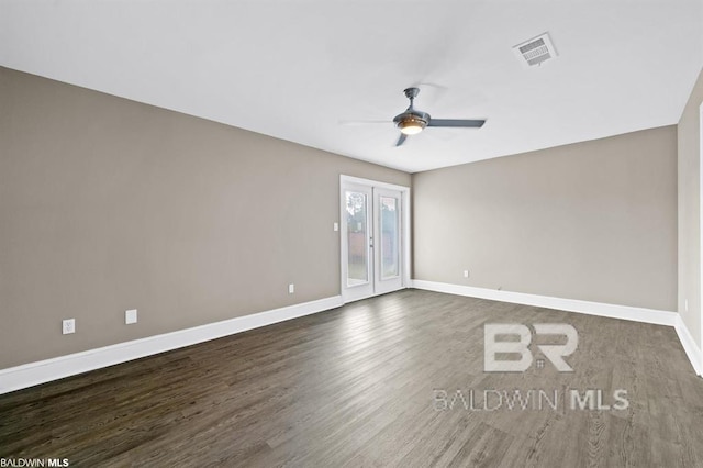 empty room featuring a ceiling fan, visible vents, dark wood finished floors, and baseboards