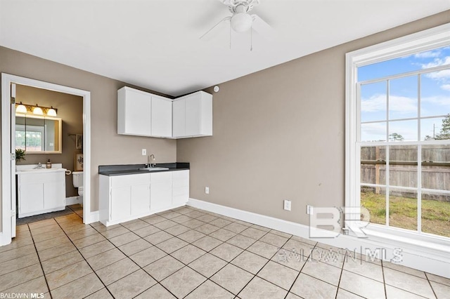 kitchen with white cabinetry, a sink, baseboards, and light tile patterned flooring