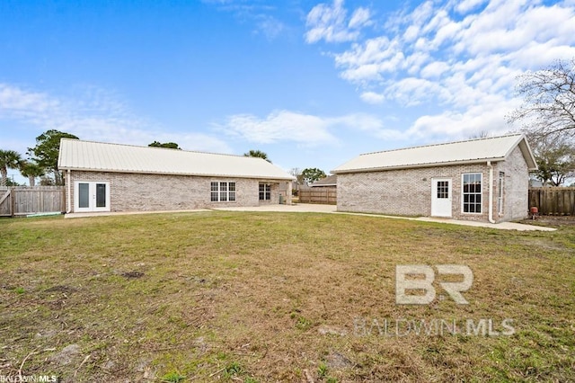 rear view of property featuring french doors, brick siding, a yard, metal roof, and a fenced backyard