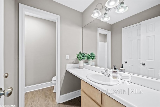 bathroom featuring baseboards, vanity, toilet, and wood finished floors